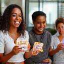 Grupo de personas riendo y compitiendo amistosamente en un juego educativo sobre alimentación saludable.