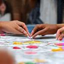 Manos trabajando en una actividad grupal interactiva sobre nutrición con materiales coloridos.